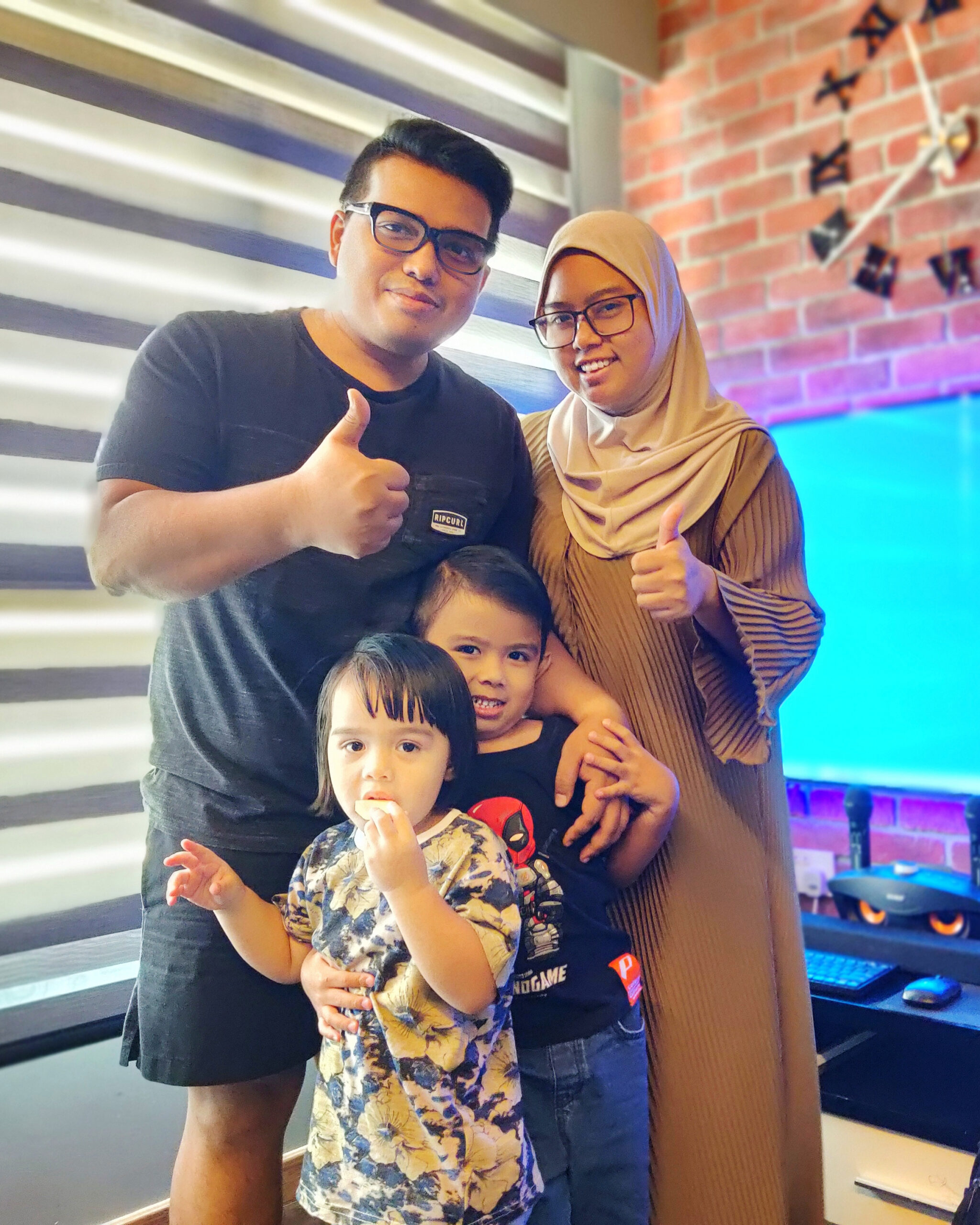 A family of four, including two adults and two children, smiling and giving thumbs up, representing satisfied PCExperts101 customers in Singapore.