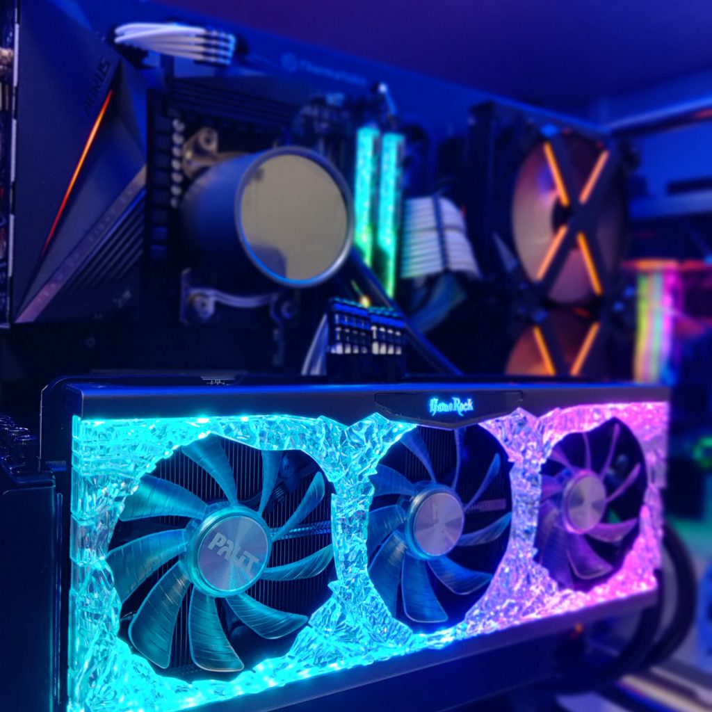 Close-up of a Palit GameRock graphics card with vibrant teal and purple RGB lighting, prominently featured in a custom gaming PC built by PCExperts101.